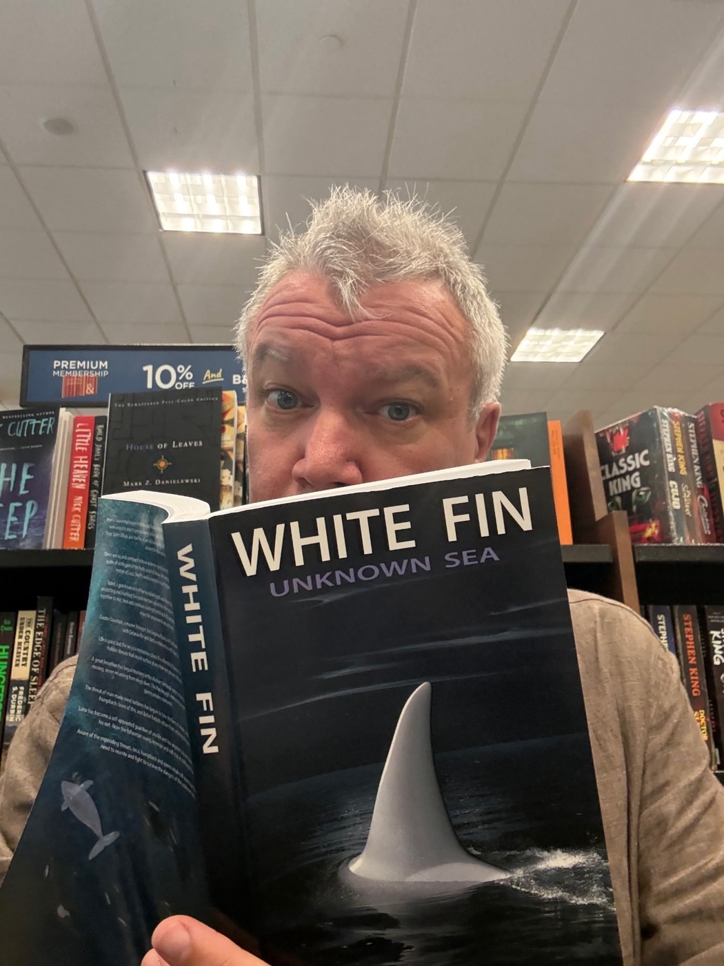 Nathan holding up a copy of White Fin: Unknown Sea in a bookstore